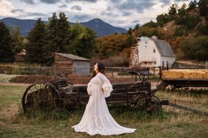 A scenic mountain landscape with rustic wooden wagons and vintage farm equipment in a rural setting at sunset.