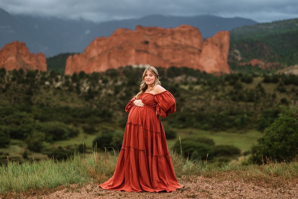 Red-clad figures stand against dramatic rock formations at Garden of the Gods in Colorado during overcast weather.
