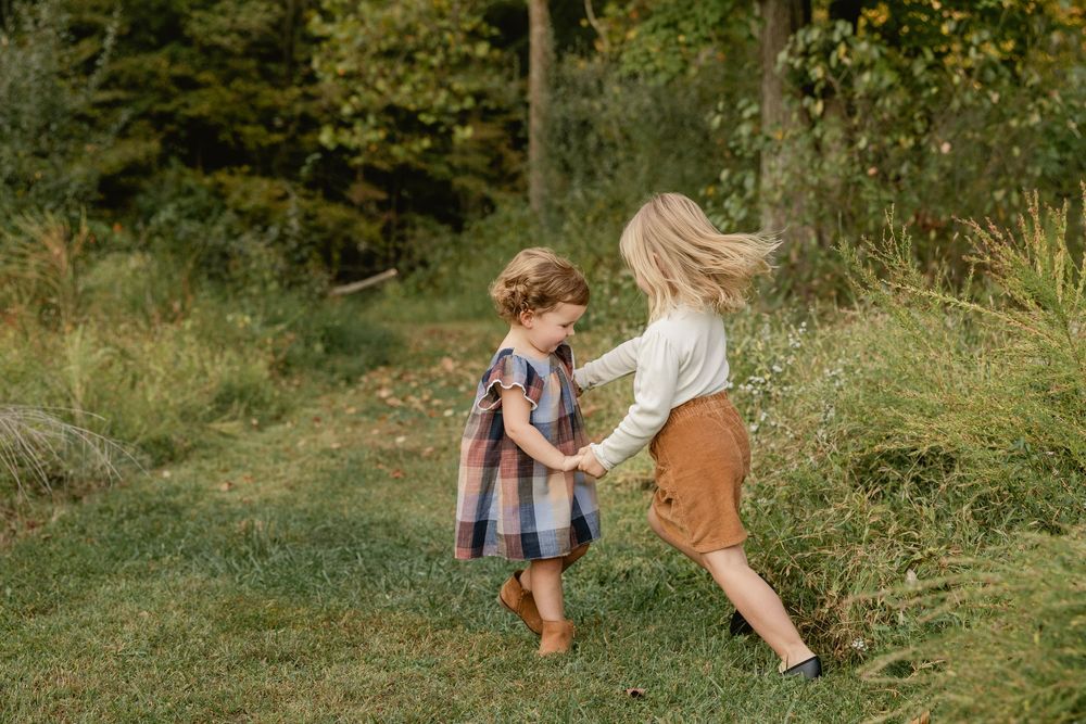 Two people walk together through a lush green meadow on a sunny summer day.