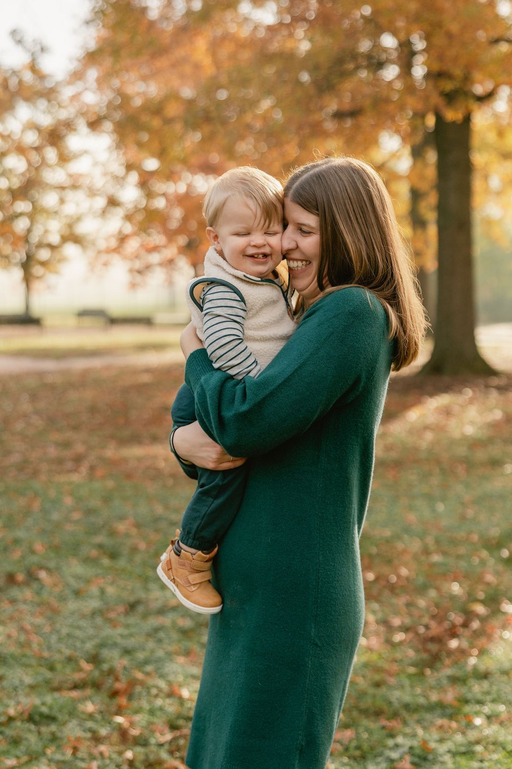 A tender embrace captured in autumn with fall foliage and scattered leaves on the ground.