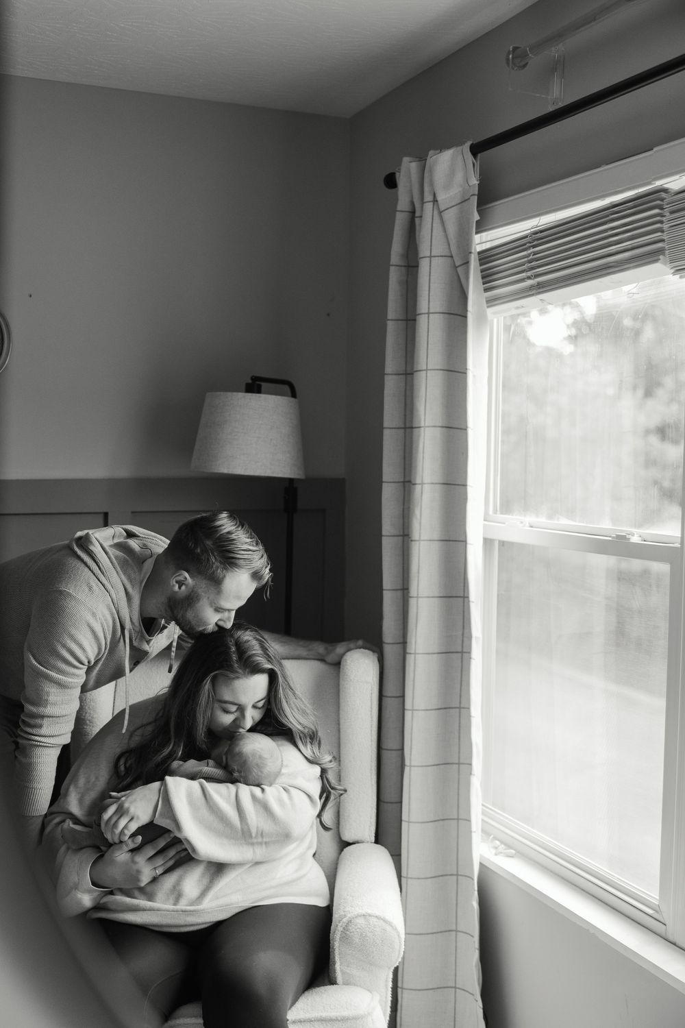 Black and white photo series showing tender moments by a window in a bright room.