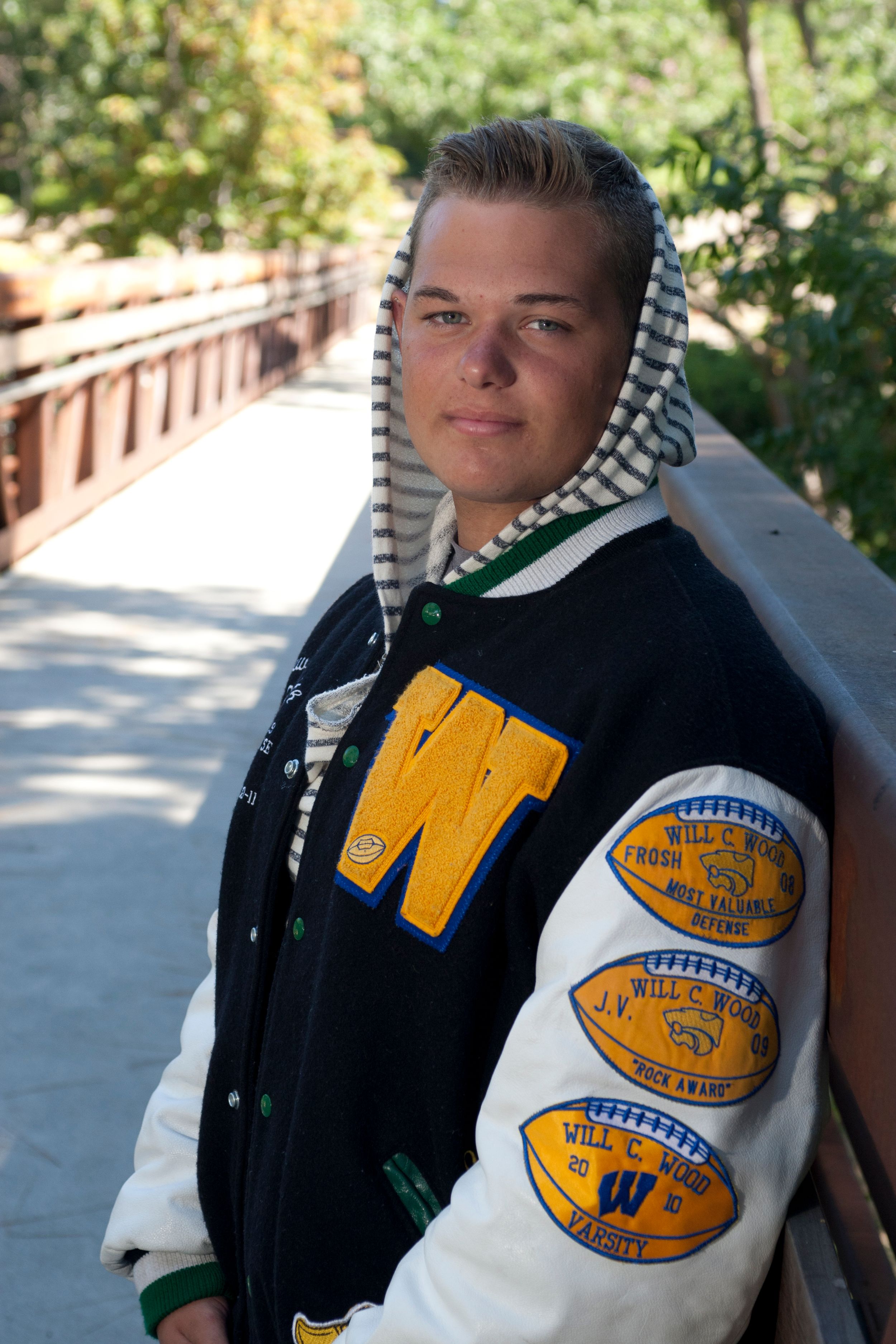 A varsity letterman jacket with yellow football patches and black and white color blocking shown in multiple angles.