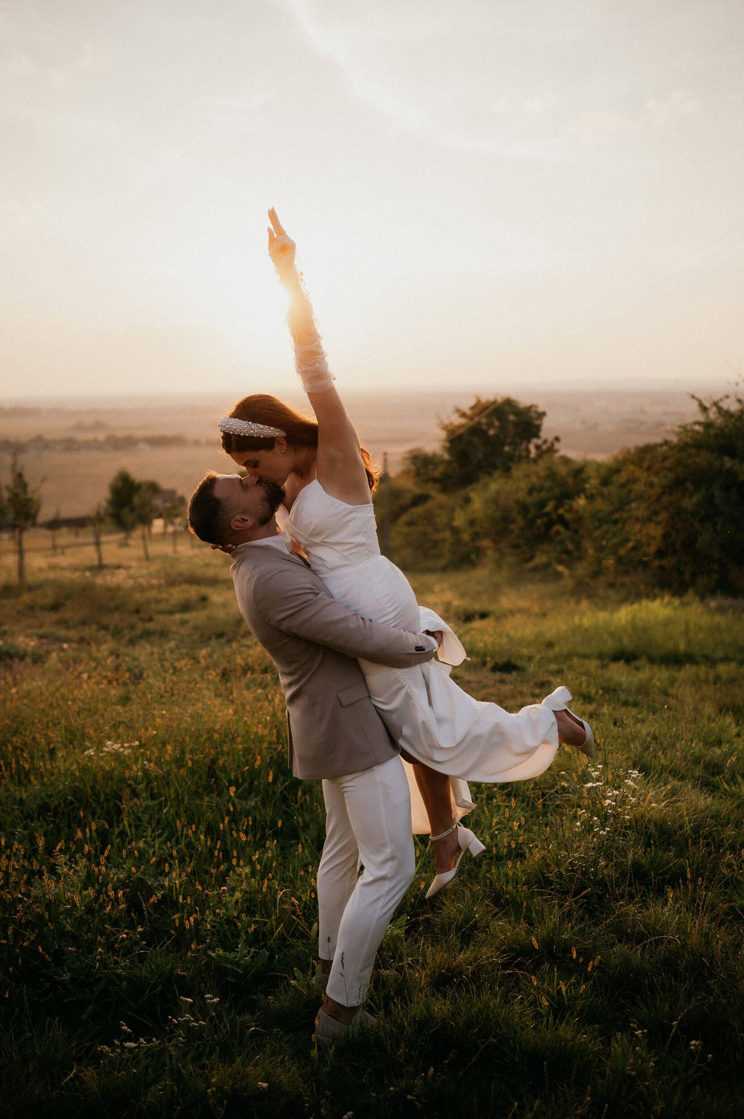 Romantic sunset wedding photo of couple dancing in a meadow.