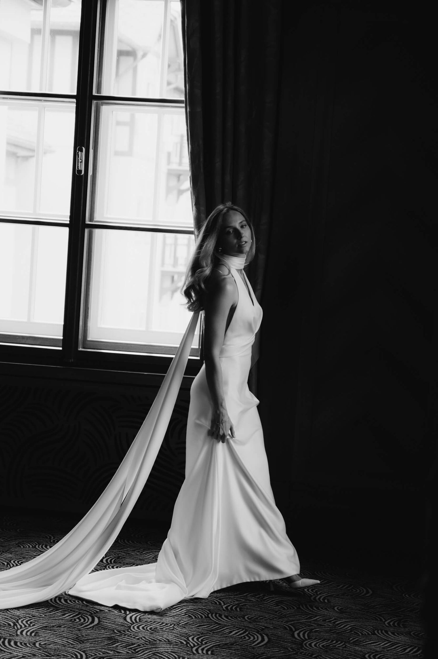 Black and white artistic series of a bride in a flowing white wedding gown with long train in dramatic lighting.