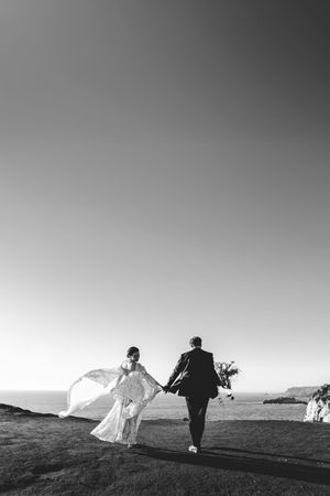 A black and white panoramic series shows a silhouetted figure walking across a mountainous landscape at sunset.