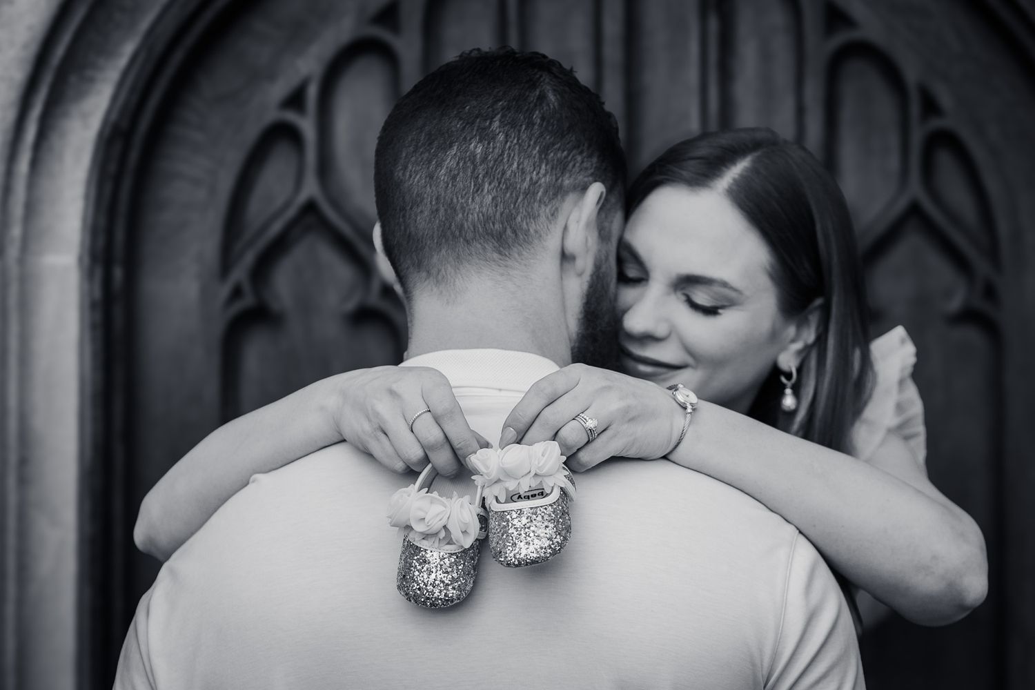Adorable baby announcement. Woman holds baby shoes behind husbands back revealing the gender