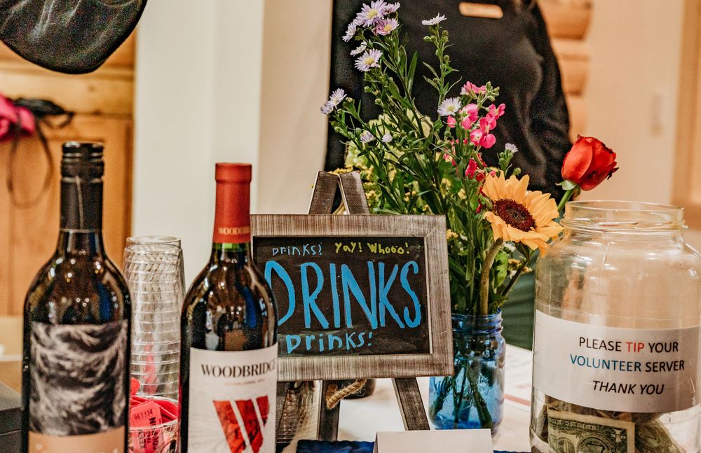 Drinks station setup with wine bottles and flower arrangements at event.