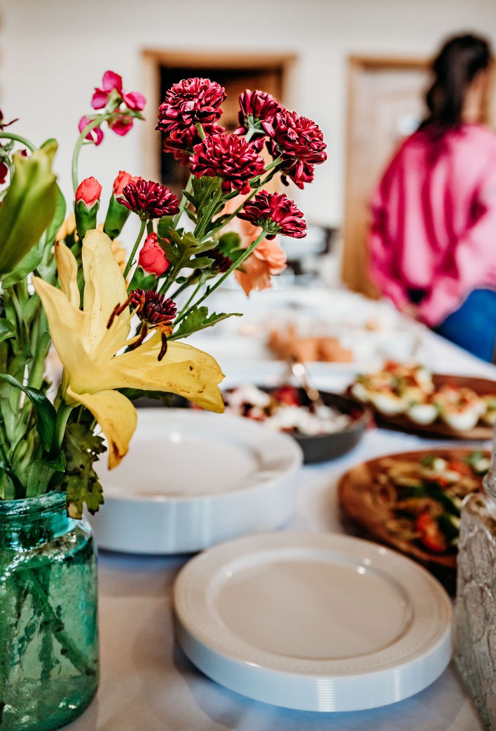 Table setting with floral centerpiece featuring burgundy carnations and yellow lily.