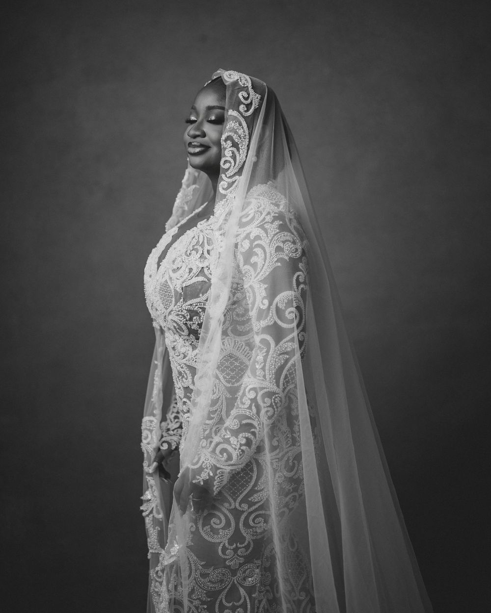 Black and white bridal portraits showcase an elegant lace wedding dress and flowing veil against a dark background.