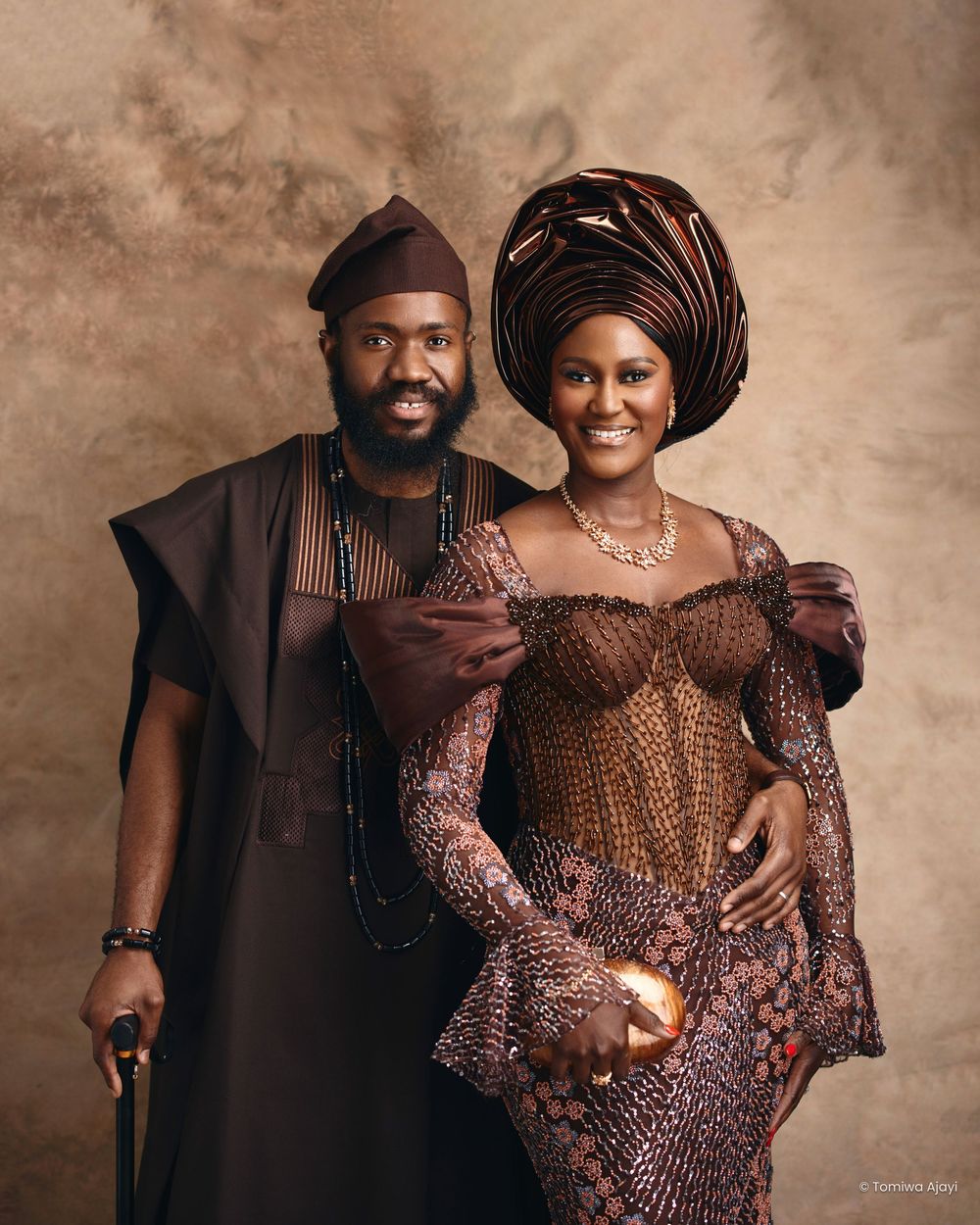 Couple in traditional African attire poses together in sepia-toned portrait series showing loving moments.