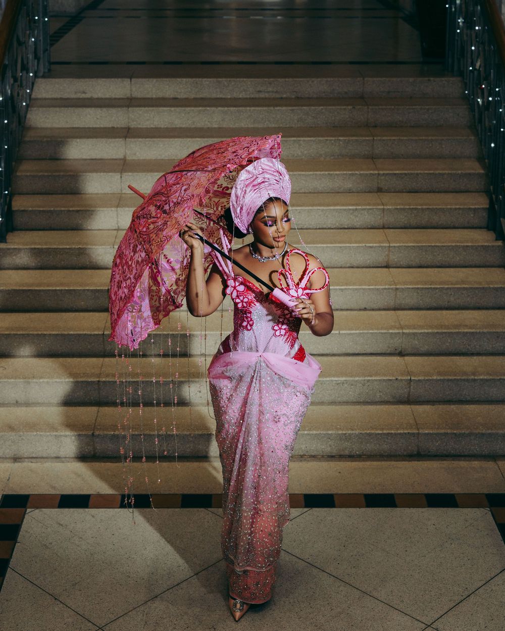 A person in a pink dress twirls with a pink parasol on stone steps in a graceful dance-like sequence.