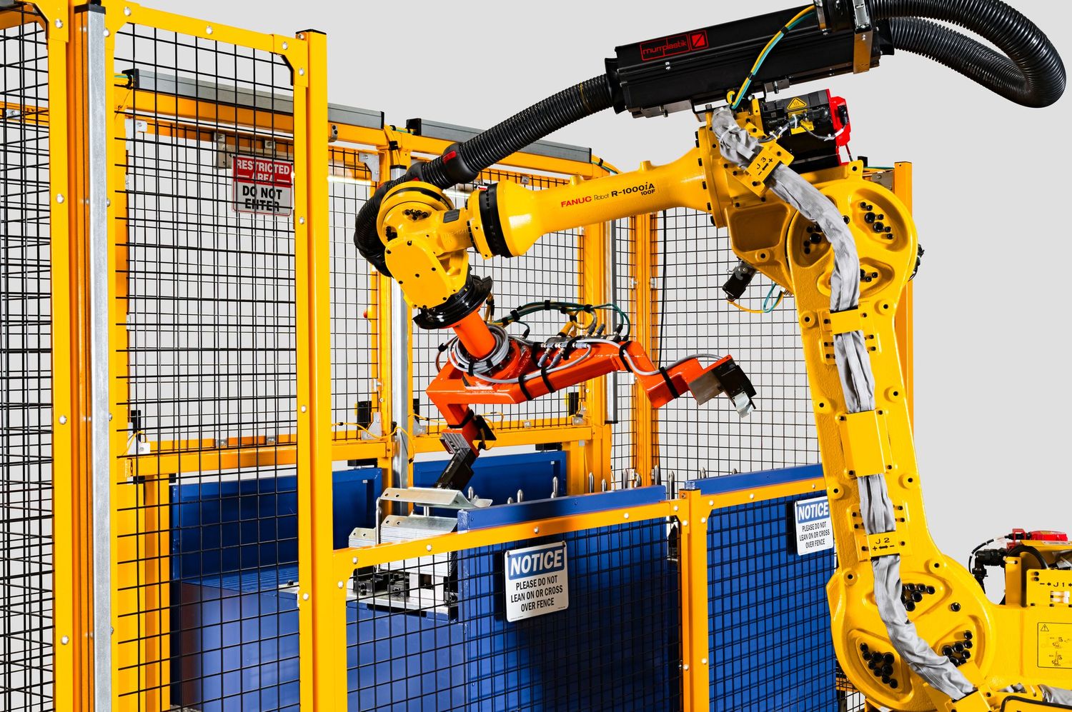 Metro Detroit Commercial photographer captures Industrial robotic arms performing automated manufacturing tasks inside safety enclosure.