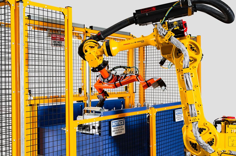 Metro Detroit Commercial photographer captures Industrial robotic arms performing automated manufacturing tasks inside safety enclosure.