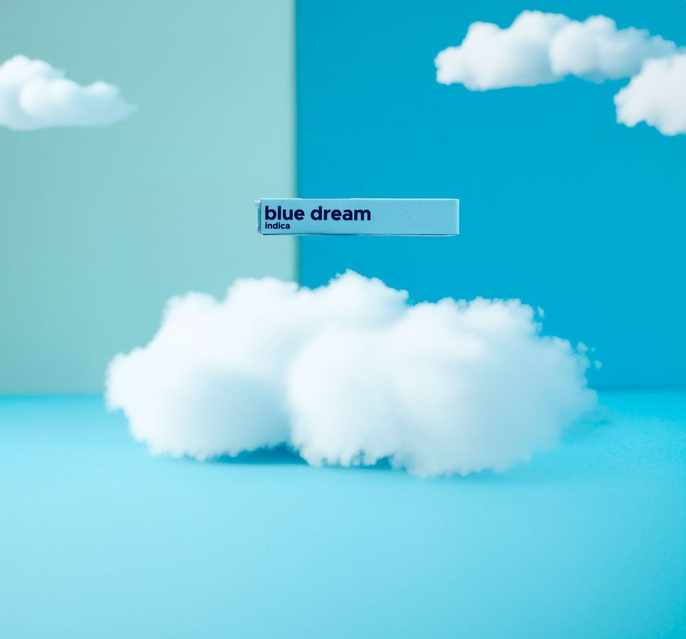 Detroit Commercial Photographer shoots Fluffy white clouds against a bright turquoise blue sky with a hovering product labeled 'blue dream'.