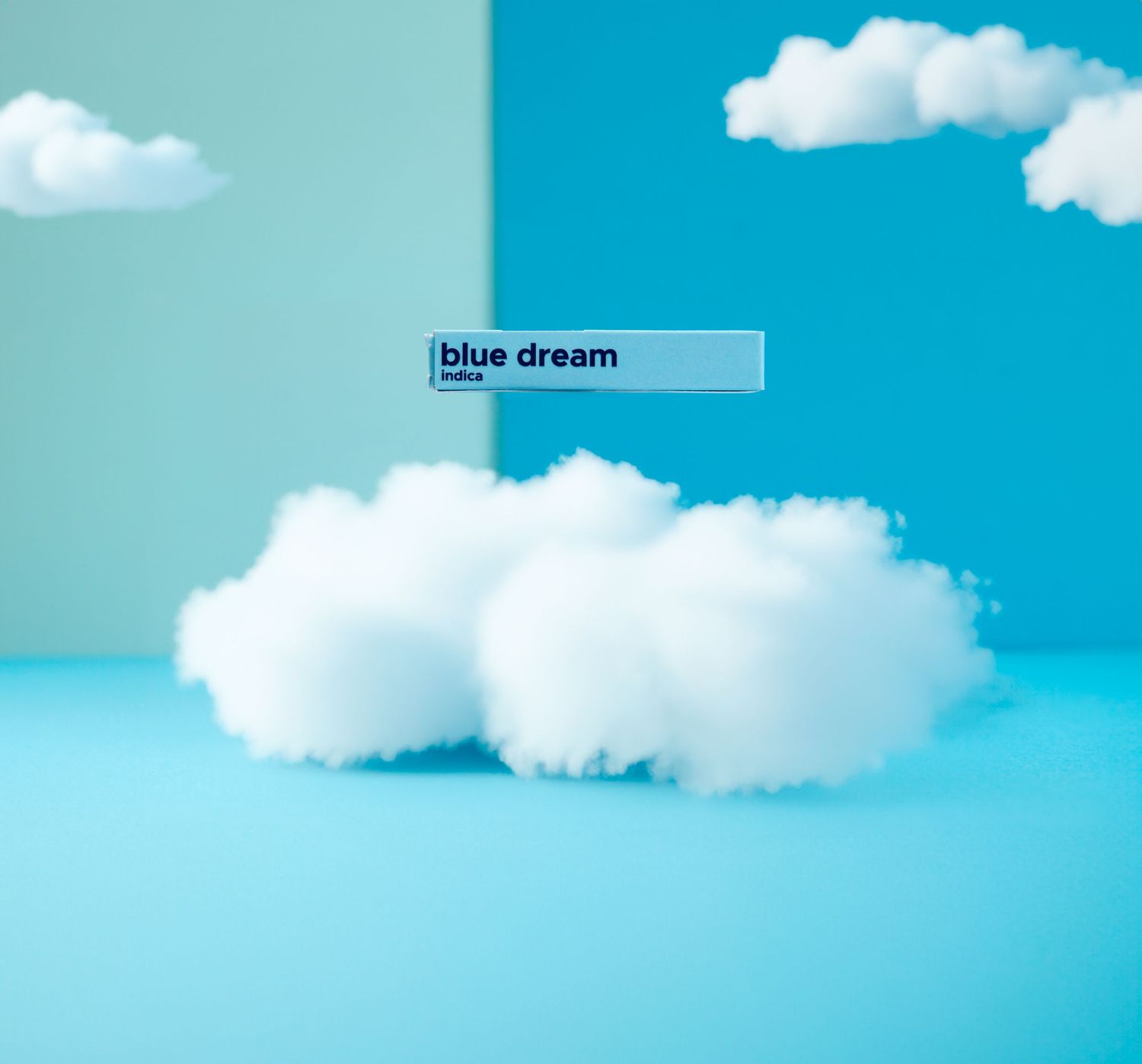 Detroit Commercial Photographer shoots Fluffy white clouds against a bright turquoise blue sky with a hovering product labeled 'blue dream'.