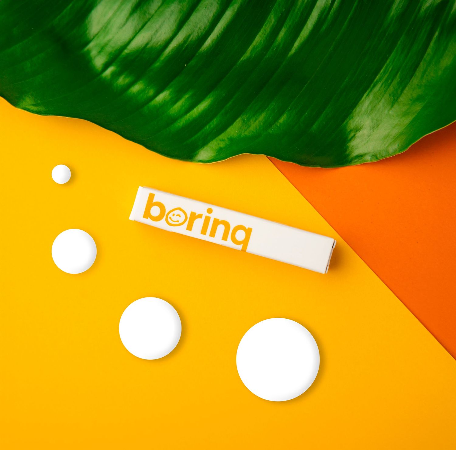 Metro Detroit Commercial Photographer captures product on yellow and orange background with 'boring' text and green leaf accent.