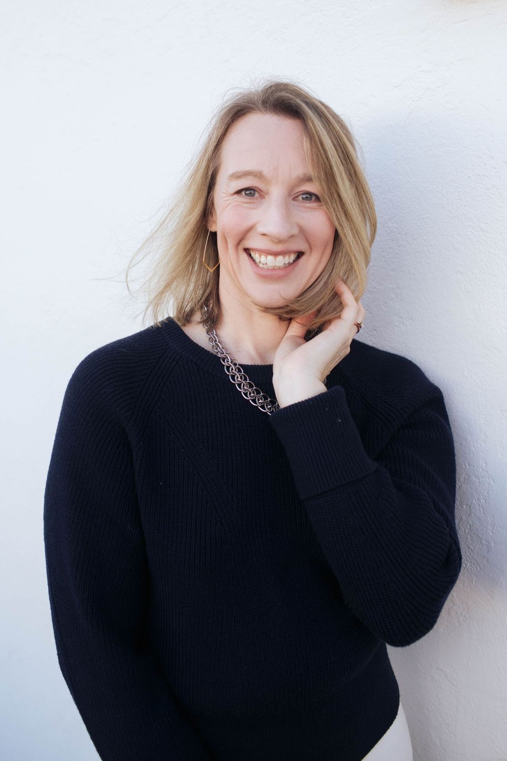 A photo of a woman outdoors in a black sweater posing playfully against a white background | Seattle headshot photographer