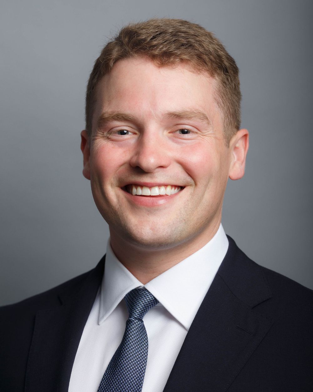 Edmonds WA Headshot photographer: A young man in a suit and tie against a gray background