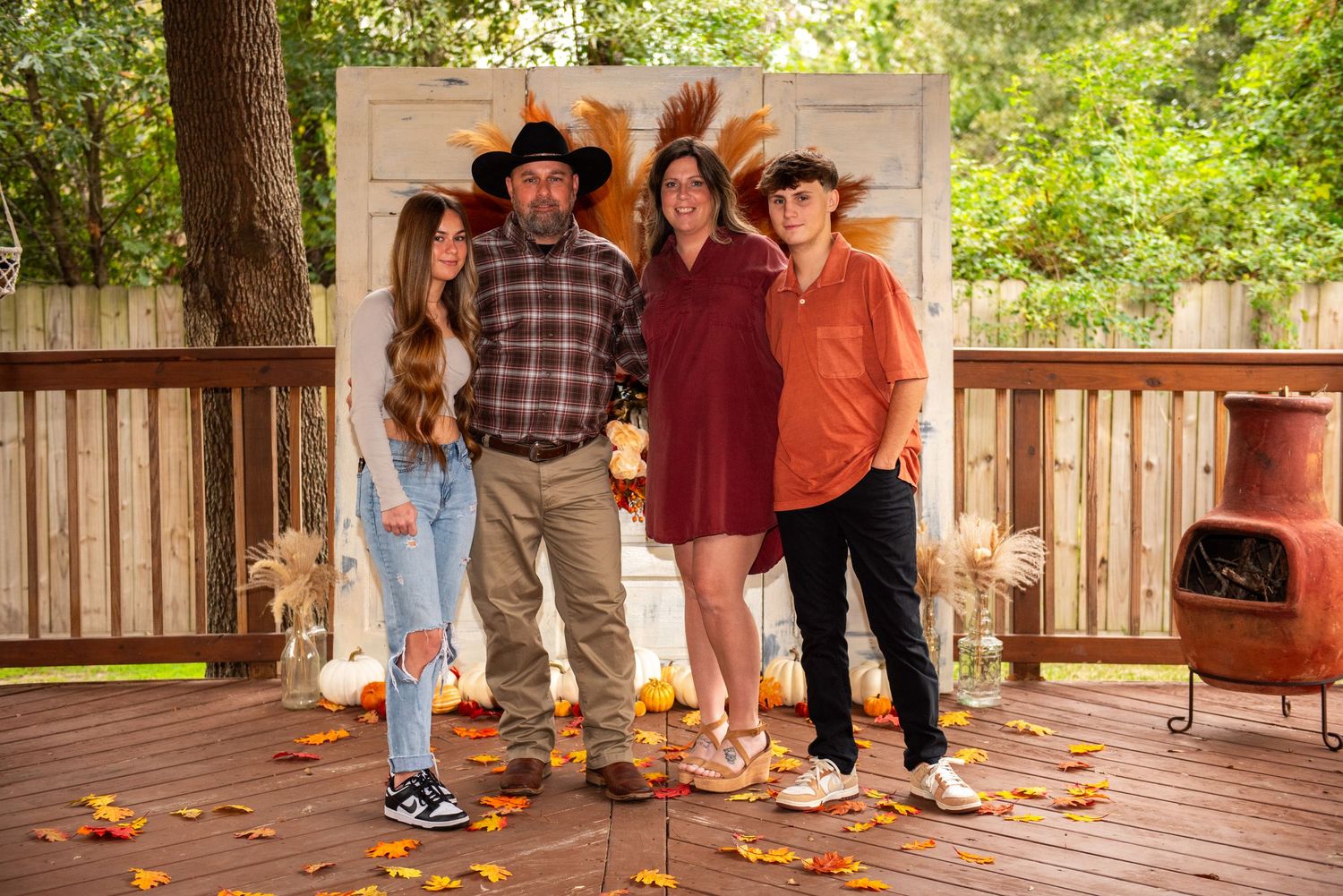 family image mom, dad, son, daughter thanksgiving time dressed nice smiling on back porch woodsy setting