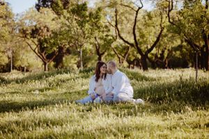 Family relaxing together on a grassy hillside during golden hour.