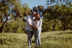 Couple walking together through a grassy field on a sunny day.