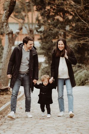 Family walking together along a path near trees and water.