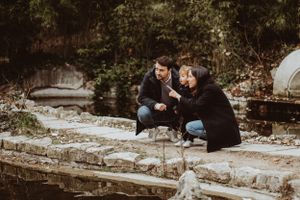 Family spending time together near a stone wall by the water.