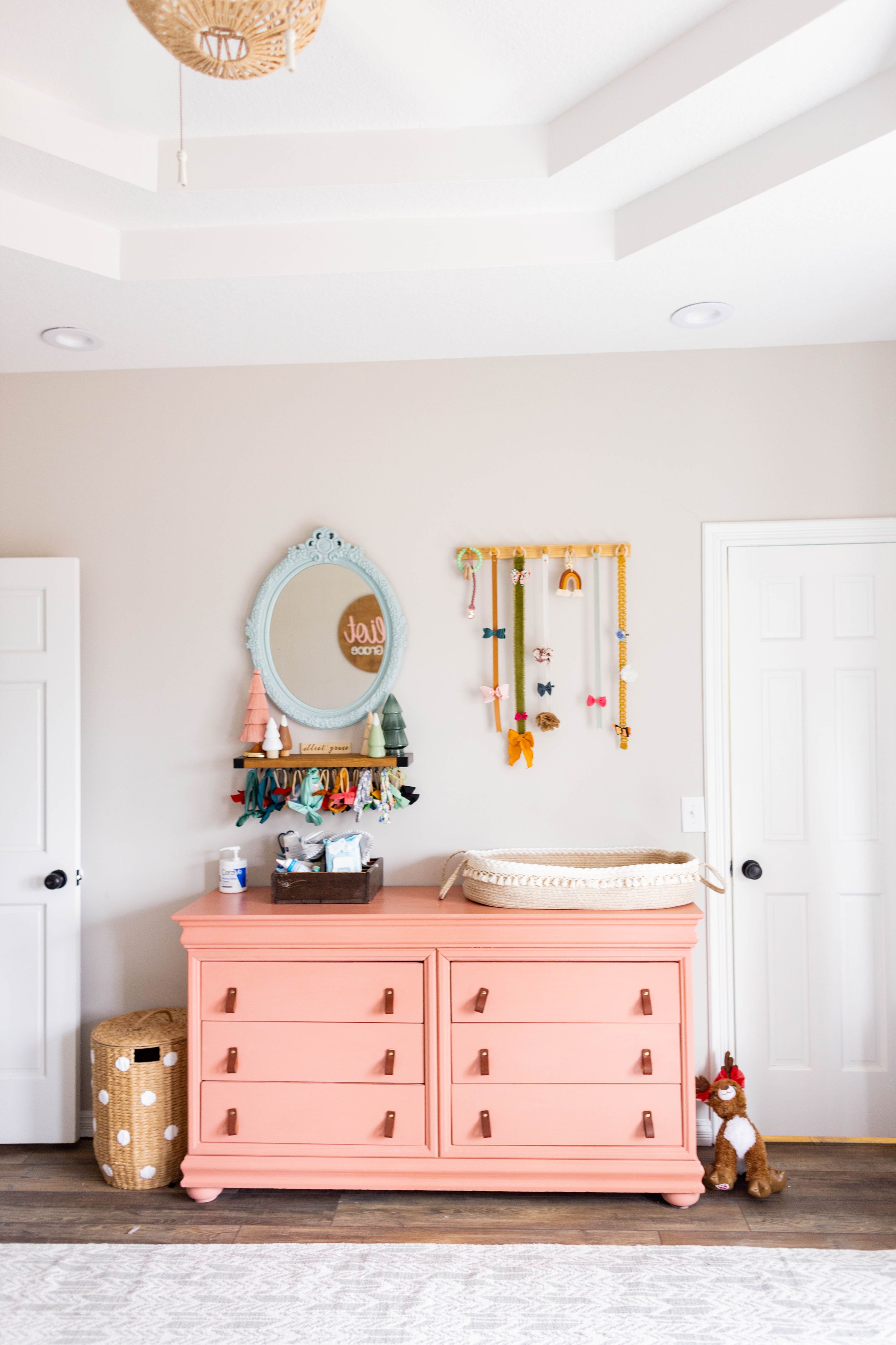 Coral dresser with changing pad and decorative mirror in a bright nursery room taken during a lifestyle session in Springfield, Missouri.