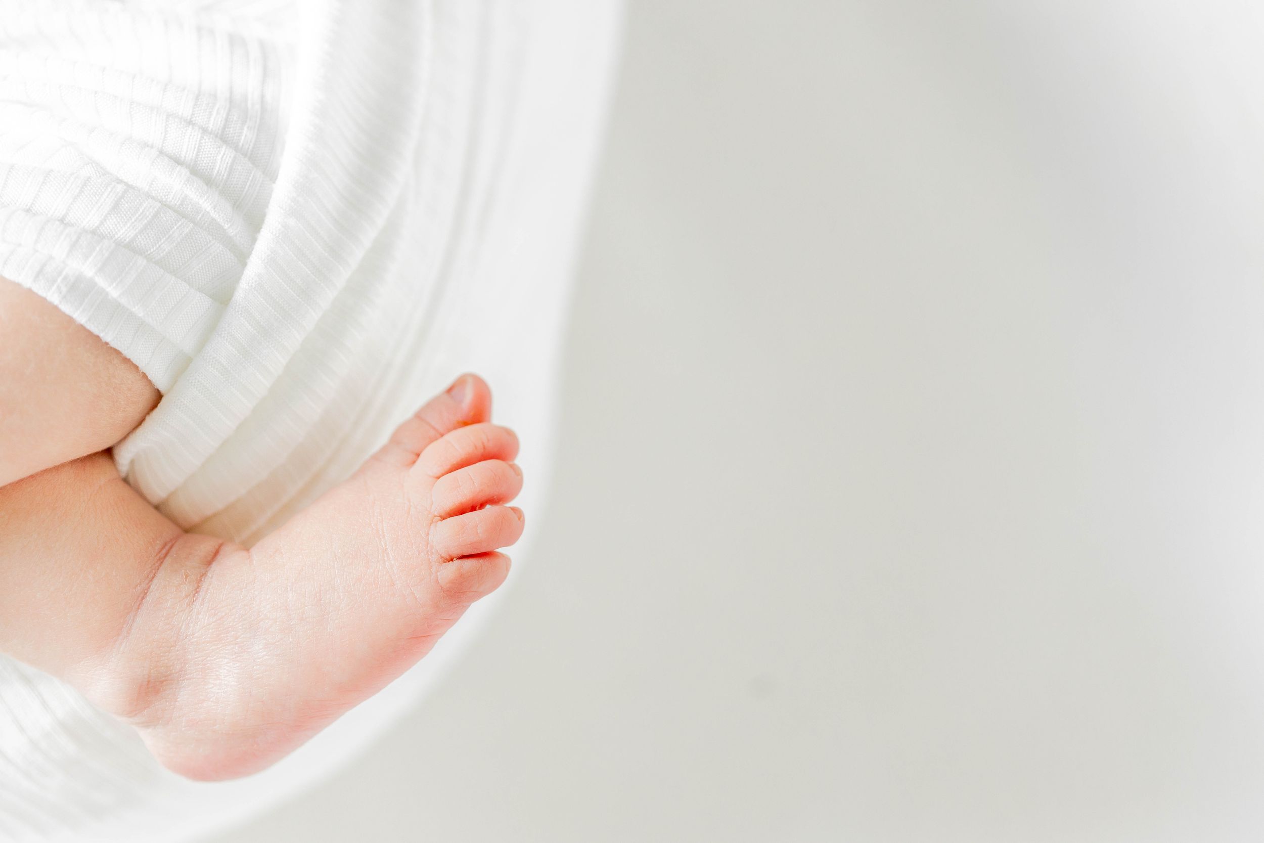 Close up of tiny baby feet wrapped in white fabric during a lifestyle session in Springfield, Missouri.