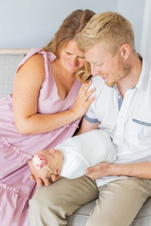 Parents share an intimate moment while cradling their newborn baby on a couch during a lifestyle session in Springfield, Missouri.