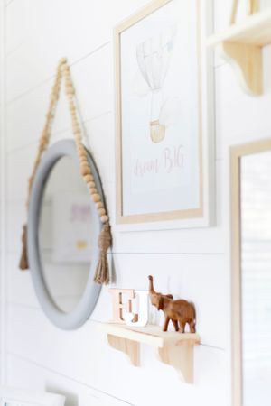 Minimalist nursery wall decor with round mirror, wooden elephants, and framed art taken during a lifestyle session in Springfield, Missouri.