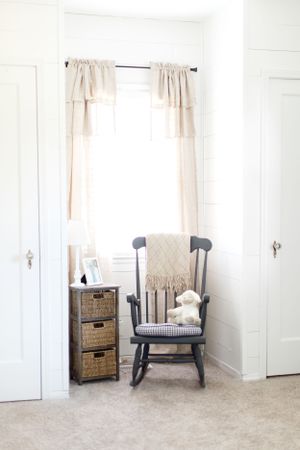 A cozy gray rocking chair with a cream throw blanket in front of a window during a lifestyle session in Springfield, Missouri.