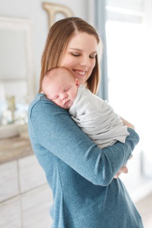 Sweet moment shared in bright nursery of a mother holding her newborn baby taken during a lifestyle session in Springfield, Missouri.