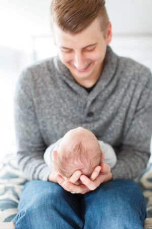 Tender moment captured in soft lighting of a father holding a newborn during a lifestyle session in Springfield, Missouri.