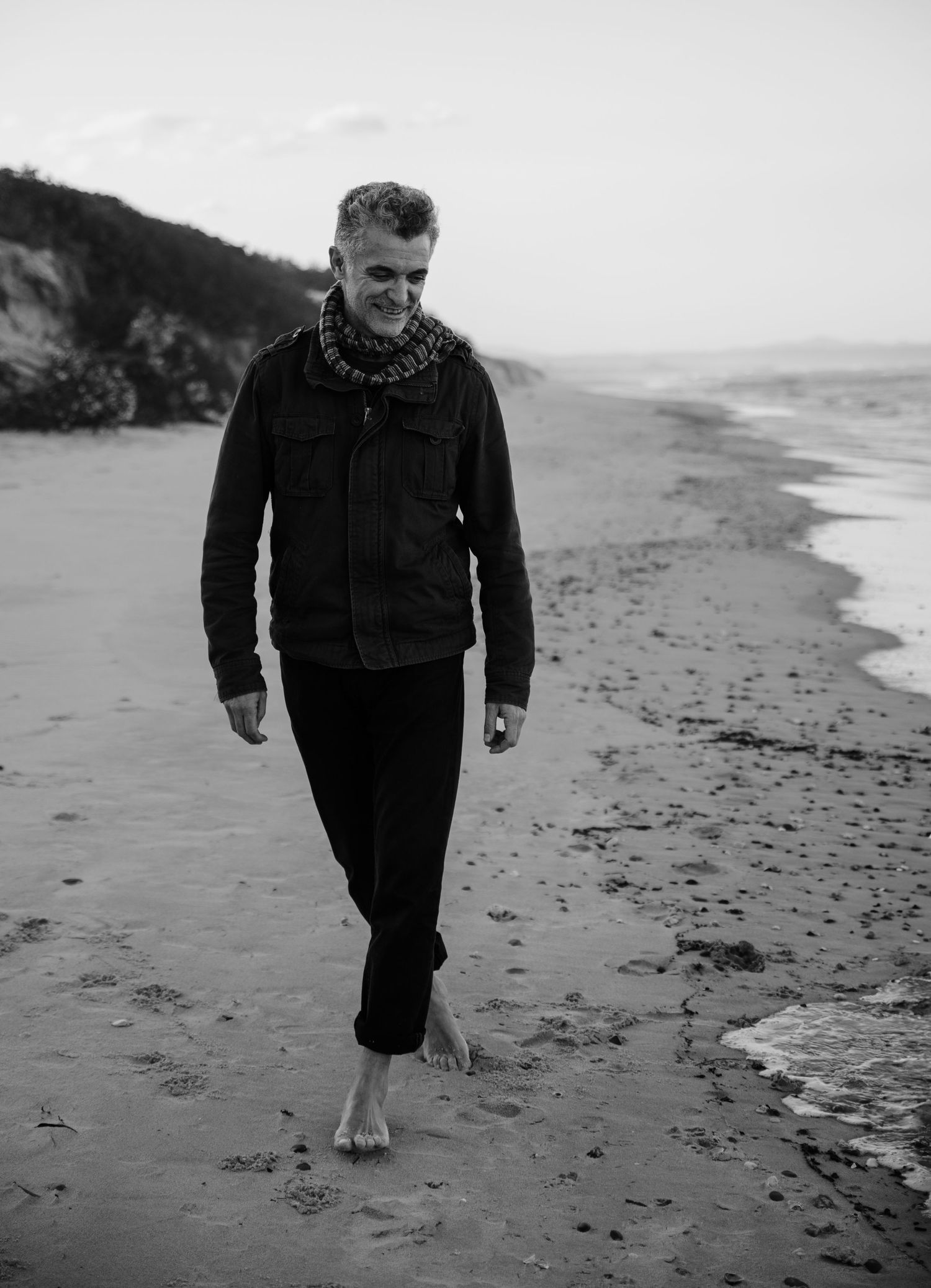 Black and white sequence of someone walking along a beach shoreline.