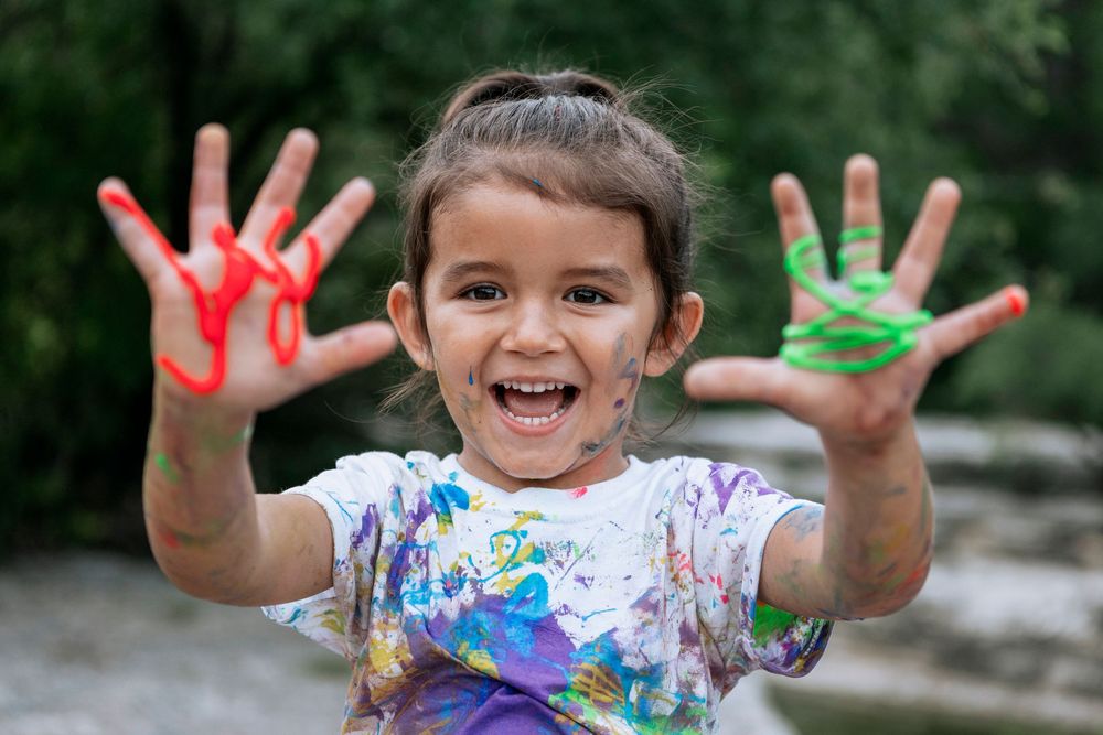 A series of six photos showing messy colorful paint-covered hands held up to the camera during a creative art session.
