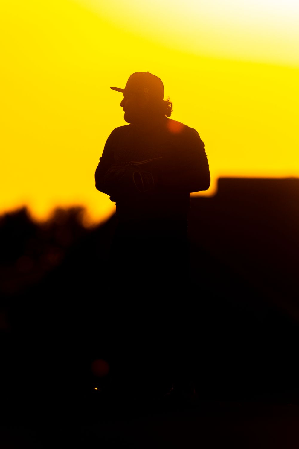 A sequence of silhouetted figures against a vibrant yellow sunset sky create a dramatic cinematic panorama.
