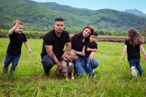 Playful family moment with their dog in a mountainside meadow.