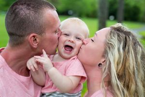 A child laughing with joy while being embraced and kissed.