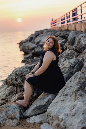 Sunset portrait session on rocky coastal shore with warm golden light.