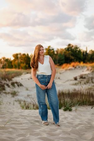 Casual beach photoshoot on sandy dunes during sunset with soft pink sky.