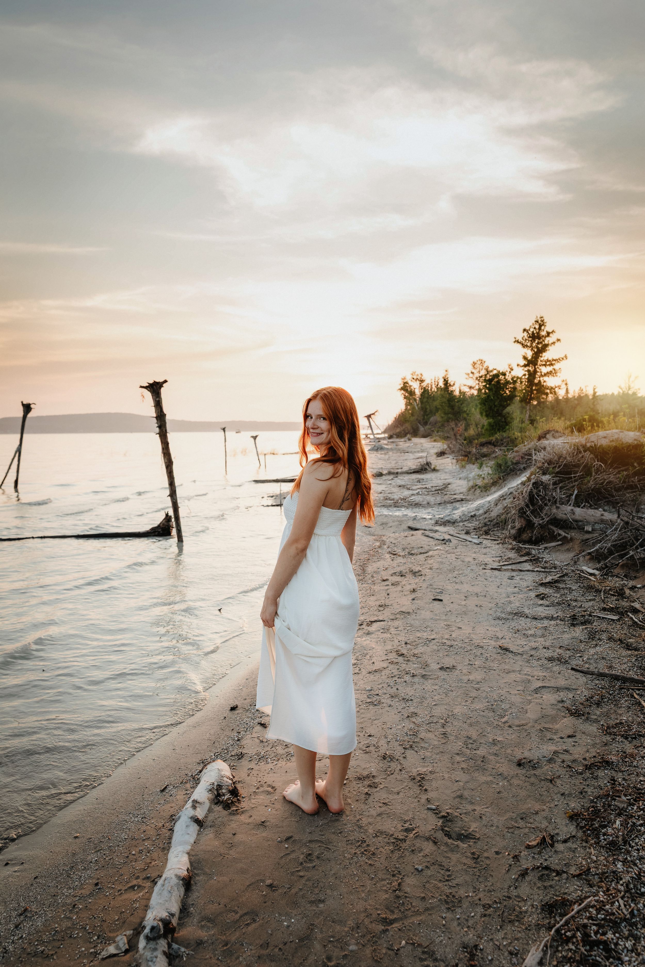White dress flowing in the breeze during beachside sunset photoshoot.