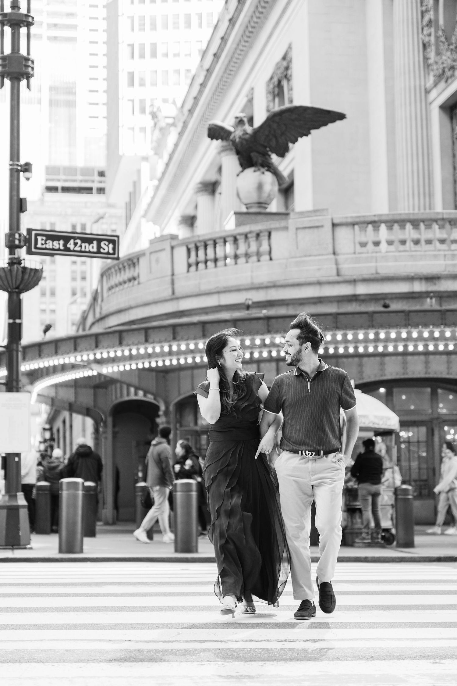 A stylish couple strolls past historic architecture on East 42nd Street in New York City.