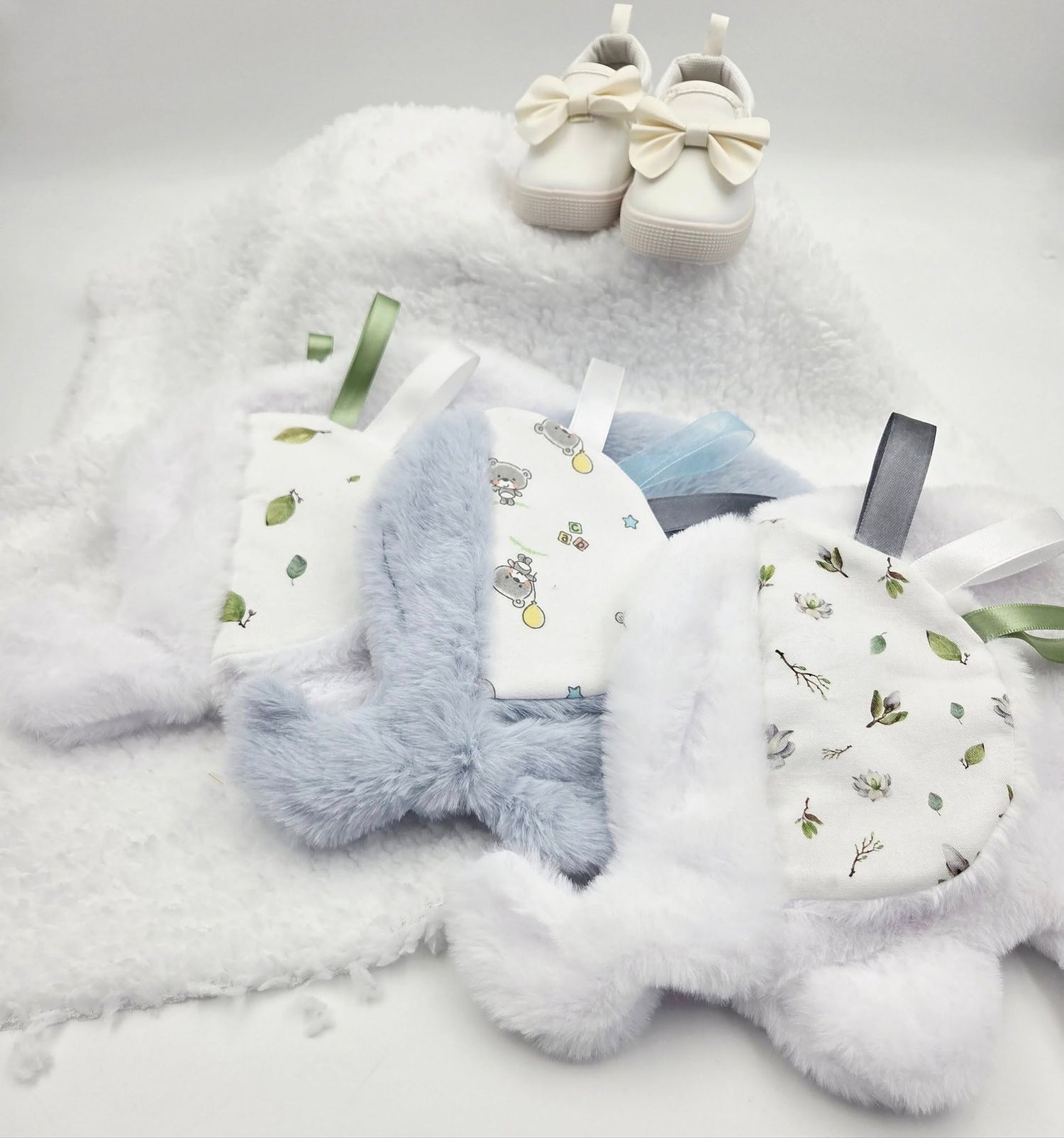 White and light blue baby accessories with floral pattern arranged on soft textured background.