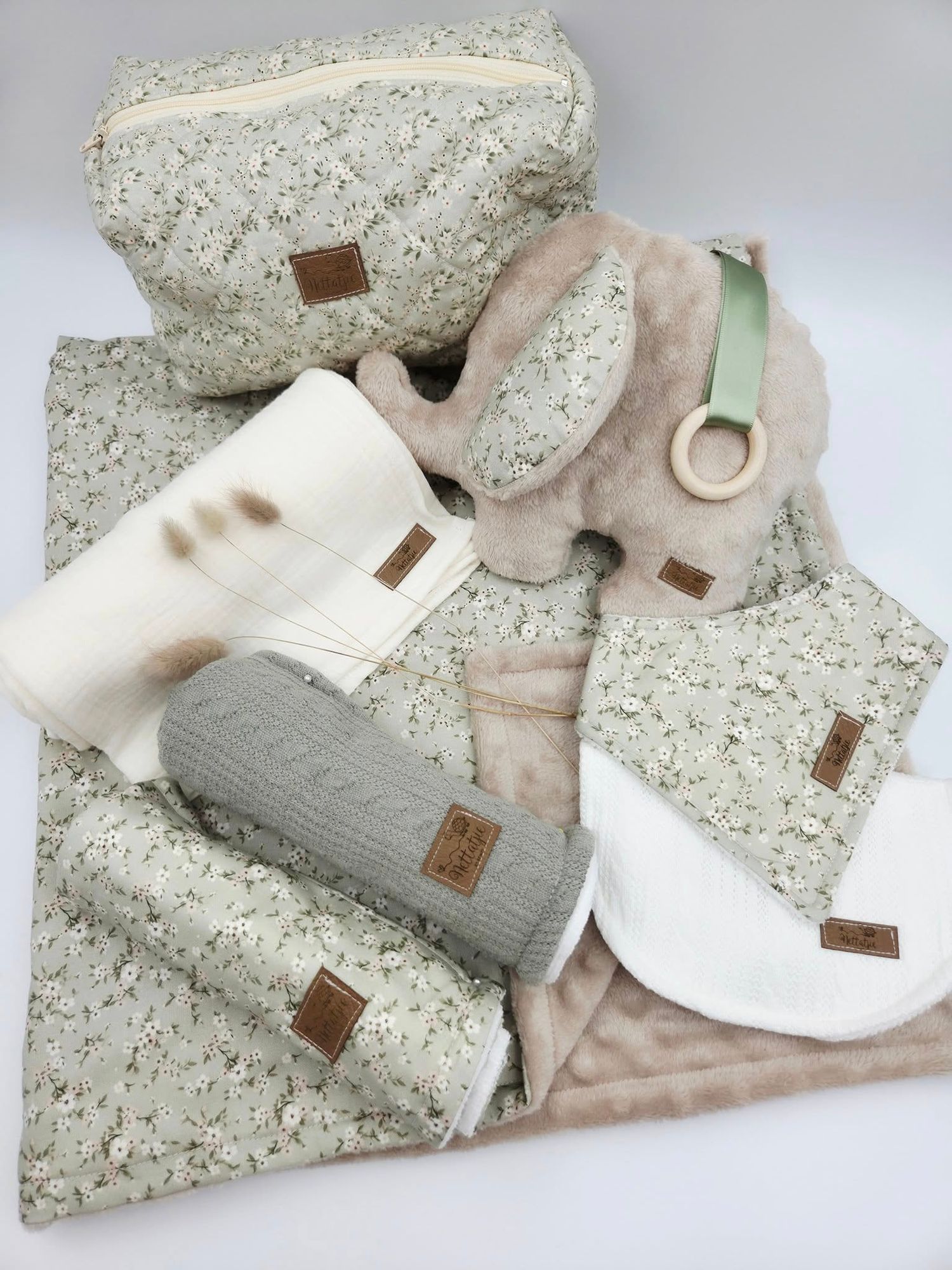 Neutral colored baby clothing and accessories arranged on speckled grey surface.