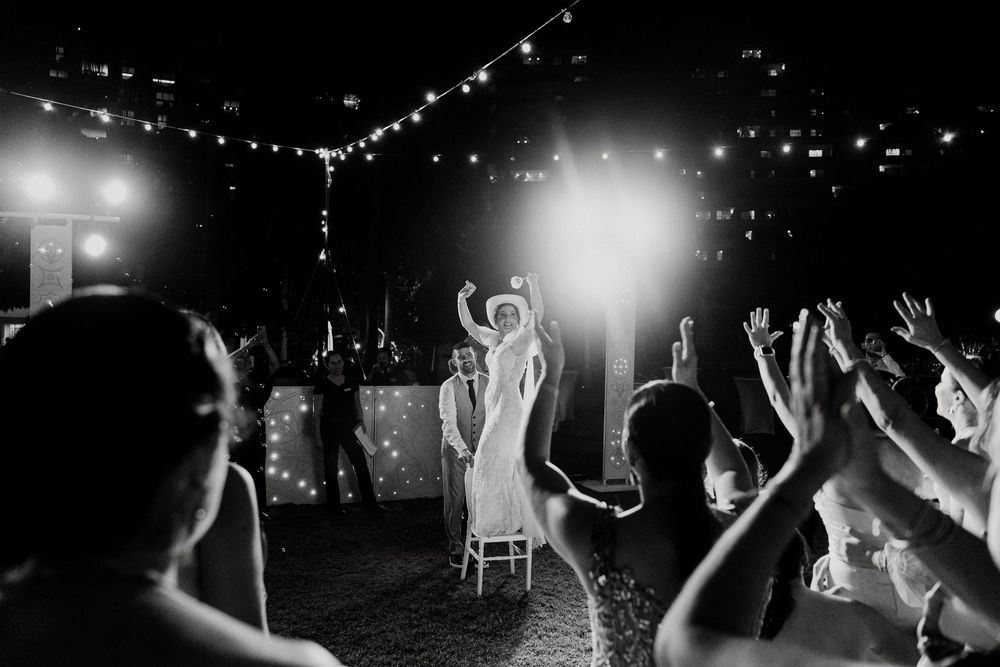 Los invitados a la boda bailan y celebran en una pista de baile tenuemente iluminada y decorada con guirnaldas de luces durante la recepción