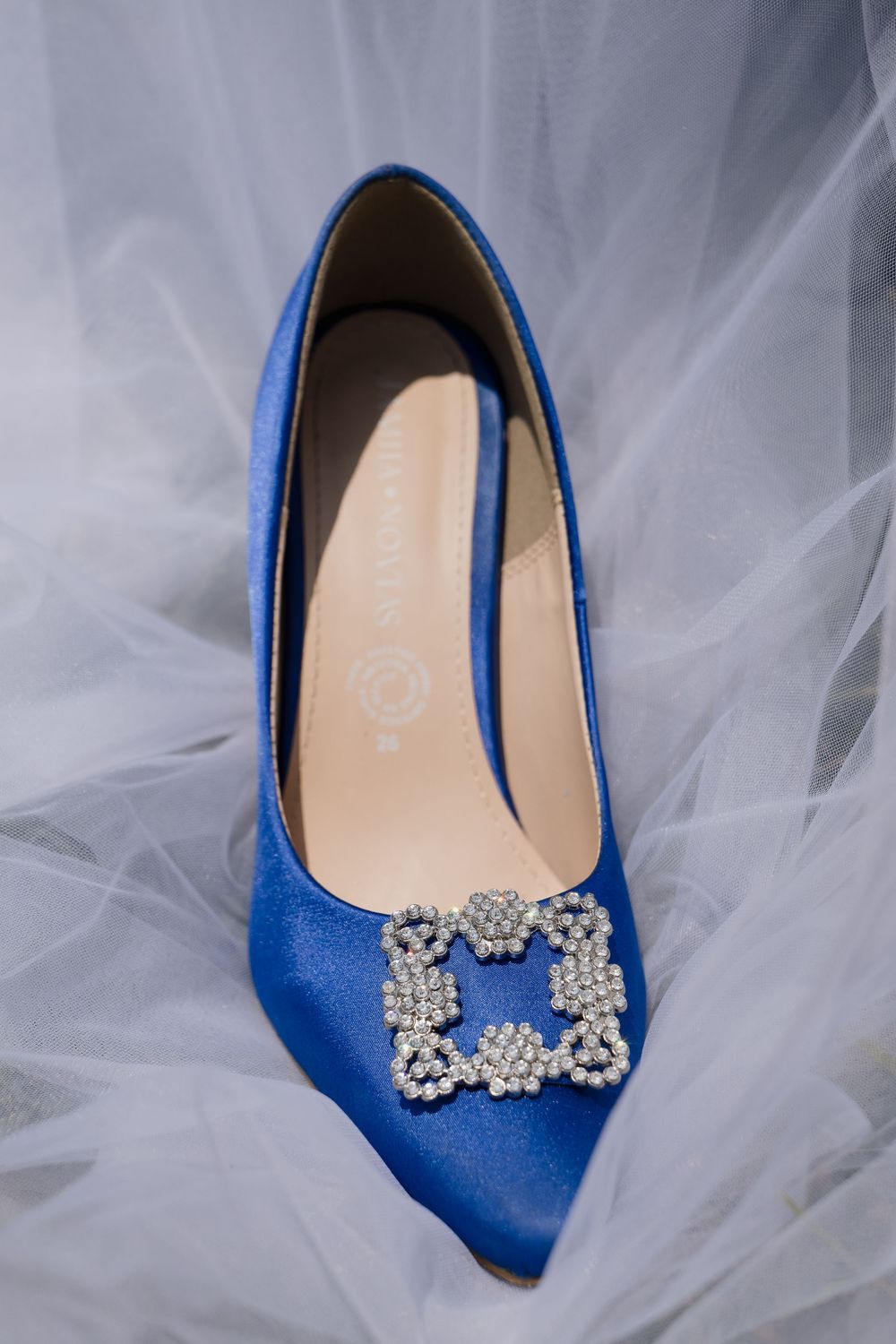 Royal blue satin heels with crystal bow embellishment on white tulle fabric.