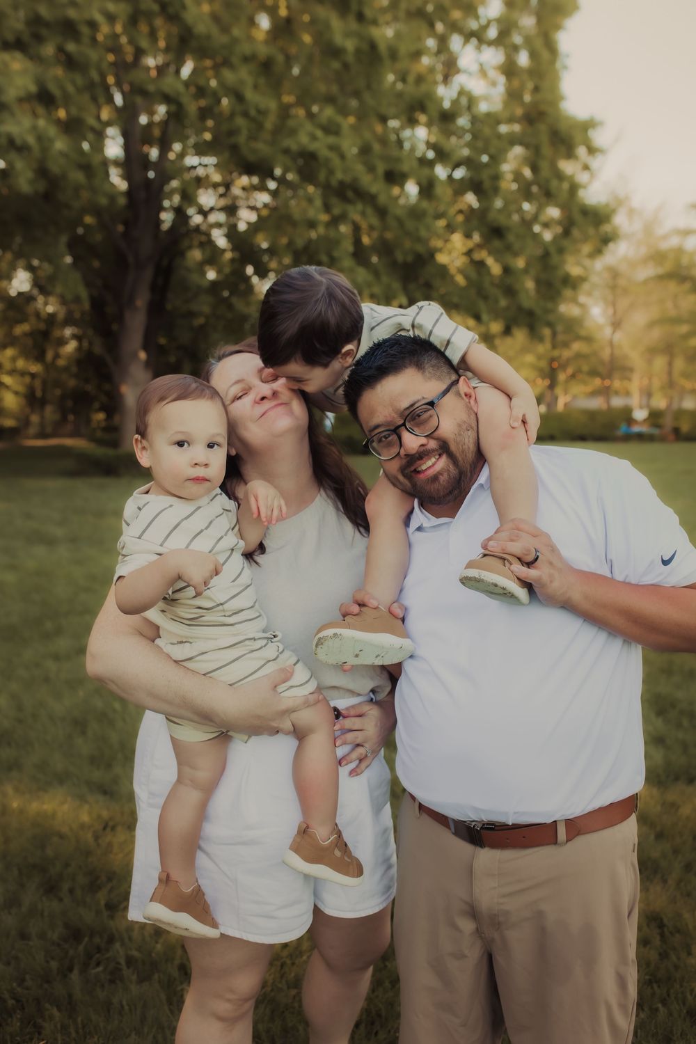 Family smiling and laughing in a field during a family session in Wimbledon