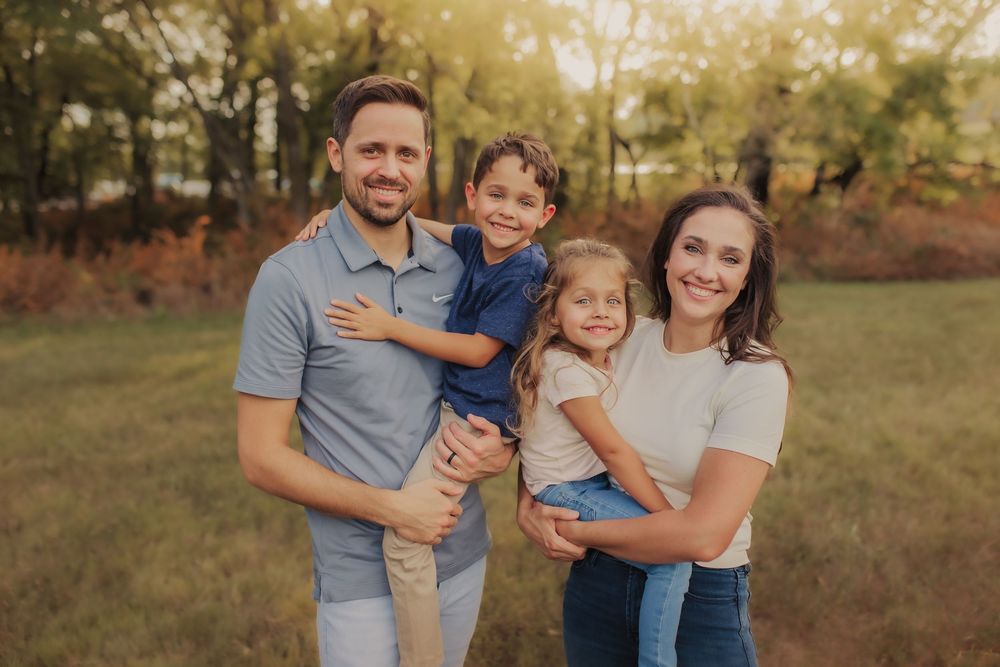 Family smiling and laughing in a field during a family session in Wimbledon