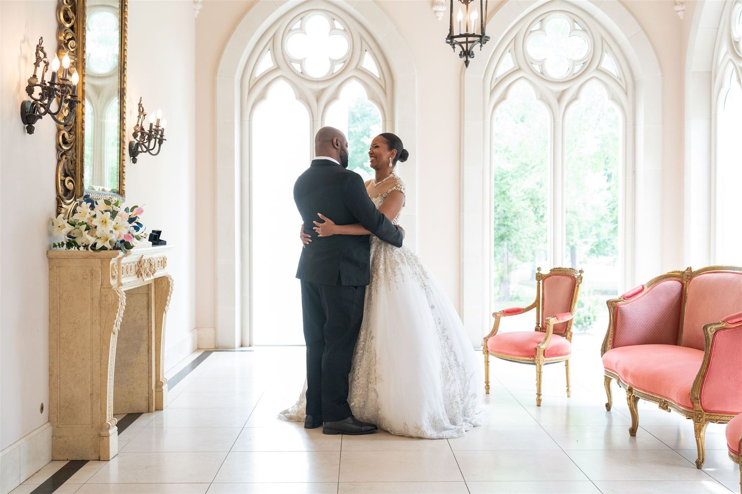 Intimate wedding portrait against Spanish tile roof and lush greenery with white floral bouquet.